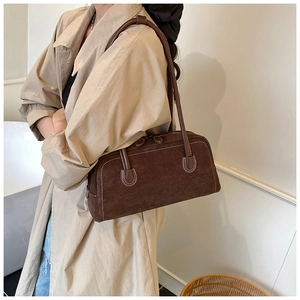 Detail of dark brown suede shoulder bag showing leather stitching and metal zipper