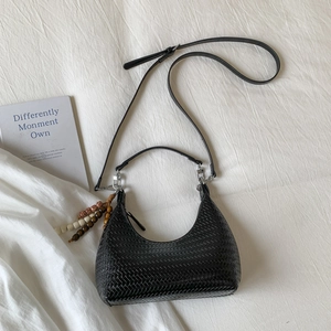 Top view of black woven moon bag with ethnic wooden bead tassels on white fabric