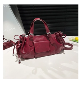 Detailed close-up of dark red pleated leather baguette bag with shiny finish and buckles