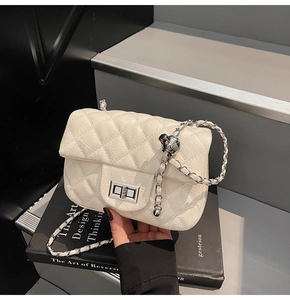 Détail du sac beige matelassé avec chaîne argentée et boucle boule ajustable en métal