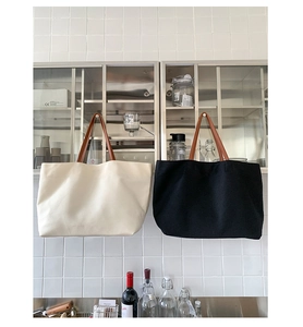 Close-up of minimalist canvas tote bags in white and black with premium leather straps