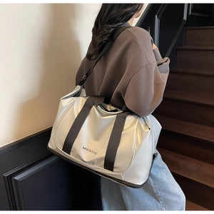 Silver metallic travel bag with adjustable black shoulder strap shown on a model