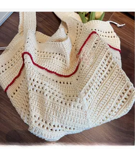 Detailed macro view of cream knitted tote bag featuring red edge trim and crochet texture