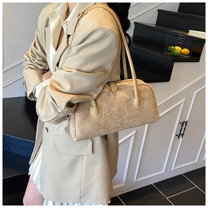 Detail of beige suede baguette bag with long straps paired with a stylish white suit