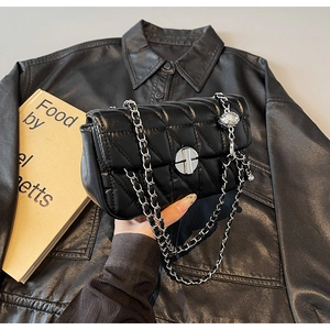 Detailed view of black quilted crossbody bag with silver chain strap and metal turn lock