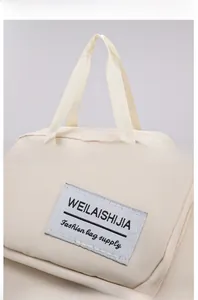 Detail of cream canvas travel bag with durable woven handles and fashion brand label