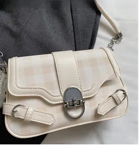 Dettaglio borsa a quadri beige con grande chiusura ovale argentata e tracolla in pelle