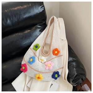 Détail d'un sac en tricot ajouré avec des fleurs en crochet 3D colorées
