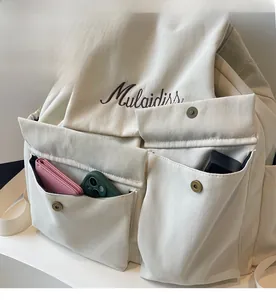 Detail of off-white canvas backpack featuring functional pockets with metal snap buttons