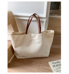Detail of canvas tote bag showing cream fabric texture and brown leather straps