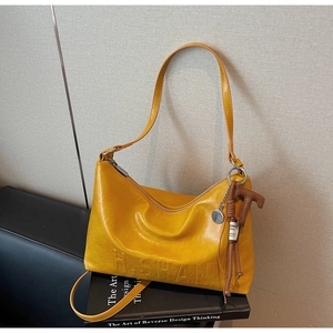 Detail of yellow leather bag with H. SHAN embossing and decorative brown charms