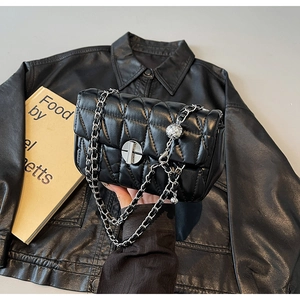 Close-up of black quilted leather shoulder bag with silver chain and metal ball charm