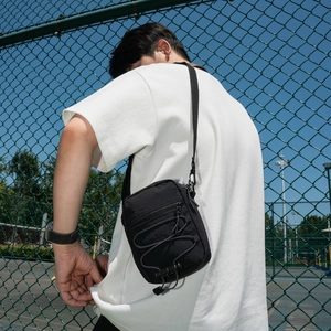 Detail of black nylon crossbody bag with elastic drawstring and adjustable strap