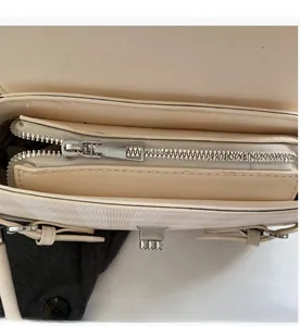 Dettaglio della cerniera in metallo argento e della fodera interna della borsa beige
