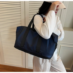 Detail of dark blue travel bag with black handles and metal buckles for yoga or gym use