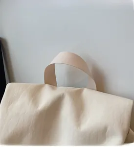 Close-up of the reinforced woven handle and textured beige fabric on the casual backpack