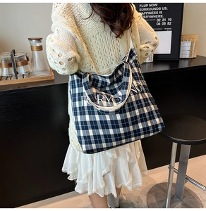 Detail of blue and white checkered canvas tote bag with FORYOUNG text on model shoulder