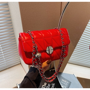 Close-up of red quilted crossbody bag with silver chain strap and metal lock closure