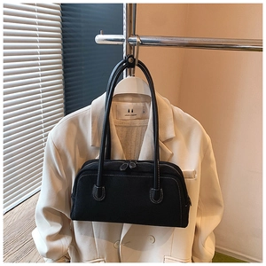 Detail view of a black canvas baguette bag with contrast white stitching and dual straps