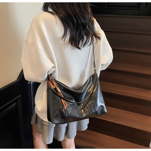 Close-up of black leather tote bag featuring H.SHAN embossed lettering and brown charm