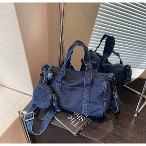 Detail view of dark blue denim cylinder bag with a detachable mini round coin purse