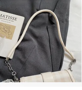 Dettaglio borsa a tracolla a quadretti beige con catena argento e ciondolo di perla