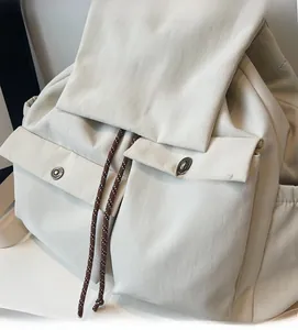 Detail view of cream casual backpack showing textured fabric and front pocket buttons