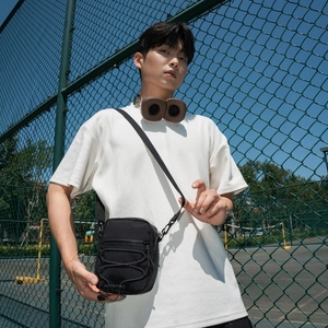 Detail view of black nylon crossbody bag with adjustable strap and bungee cord design
