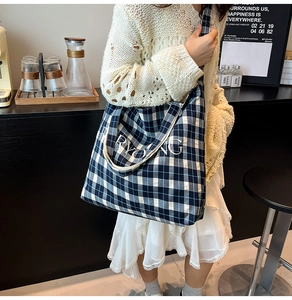 Close-up of blue and white checkered tote bag with RYONG text in casual setting