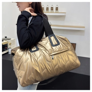 Detail of quilted metallic gold gym bag with black straps and contrast zipper pockets