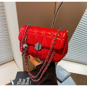 Detail of red quilted shoulder bag with silver chain and metal orb charm accessory
