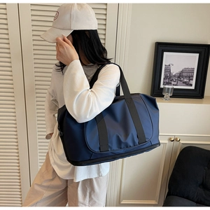 Detail of dark blue expandable travel bag with bottom zipper compartment on wood table
