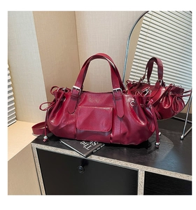 Detail view of deep red glossy leather handbag with silver hardware and drawstring accents