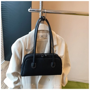 Detail of black rectangular baguette bag featuring white contrast stitching and dual zippers
