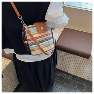 Détail du sac seau tissé arc-en-ciel avec bandoulière en cuir et accessoire de foulard