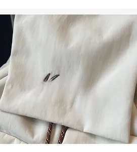 Detailed close-up of Mulaidiss embroidery on cream nylon fabric with braided drawstring
