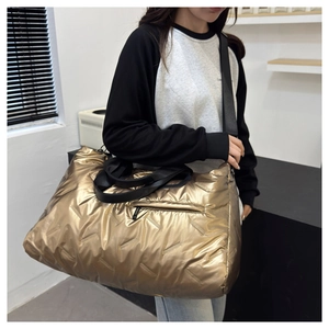 Macro detail of gold quilted puffer tote bag with waterproof finish and black straps