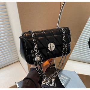 Close-up of black quilted shoulder bag with silver chain strap and metal ball charm