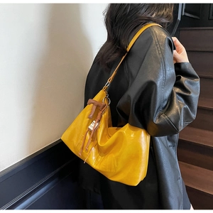 Detail of yellow PU leather shoulder bag with embossed letters and braided zipper pull