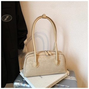 Close-up of minimalist beige suede baguette bag with dual zippers on office setting