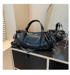 Detailed view of black pebbled leather handbag with side drawstrings and metallic beads