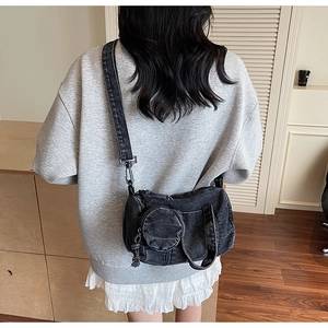 Black washed denim crossbody bag styled on model with round coin purse detail