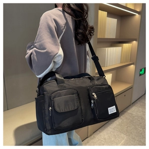 Close-up of black waterproof nylon travel bag with multi-pocket design on model