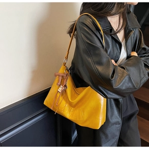 Detail of bright yellow large tote bag with embossed text and leather charm on shoulder strap