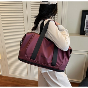 Macro detail of wine red waterproof travel bag featuring durable handles and logo