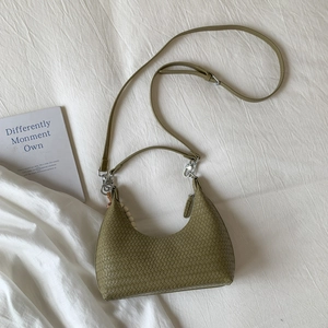 Detail of woven green crescent shoulder bag featuring silver hardware and bead charm