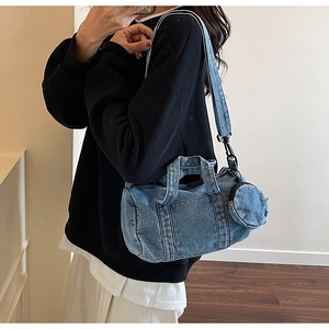 Detailed texture of light blue denim cylinder crossbody bag with mini circular coin purse