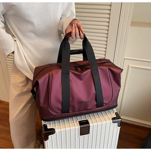 Burgundy travel bag secured on white suitcase handle, highlighting easy mobility