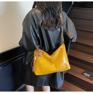 Detail view of glossy yellow leather bag with H.S.HAN embossed logo and beaded pendant
