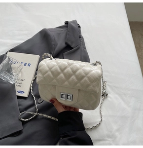 Détail du petit sac matelassé crème avec fermoir rotatif et bandoulière en chaîne
